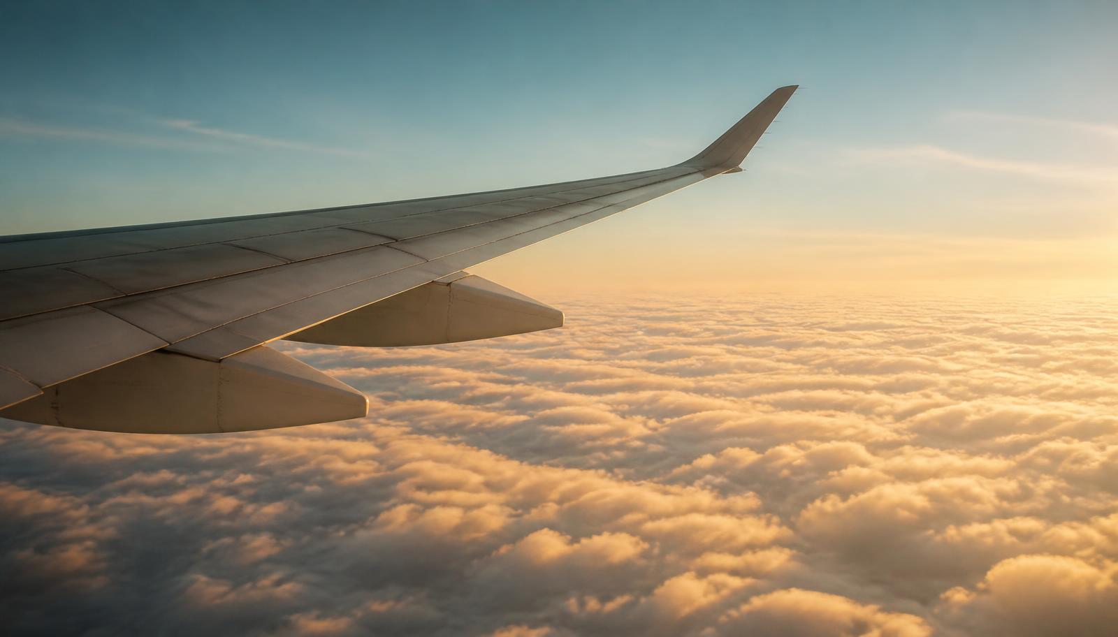 Aircraft wing above a layer of cloud at golden hour